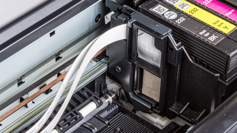 This picture shows the inside of the Epson Expression Home XP-4200 inkjet printer. You can see the printhead carriage assembly, which moves across the page thanks to the carriage drive belt. You can also see the white ribbon cable attached to the carriage, which sends electrical signals that control the printing sequence.